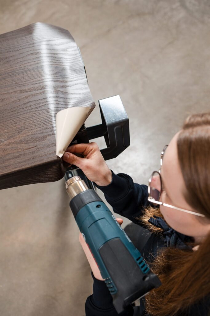 vrouw brengt houtlook vinylfolie aan op tafel met het wrappen van renowrap