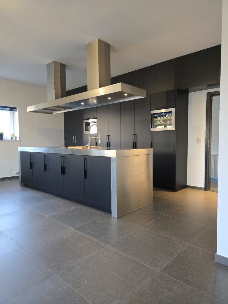 modern uitgeruste keuken met zwart gewrapte kasten en roestvrijstalen werkblad en afzuigkap